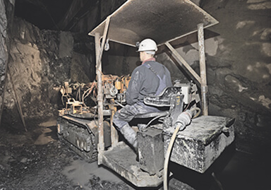 A worker sits in an excavator in the mining shaft